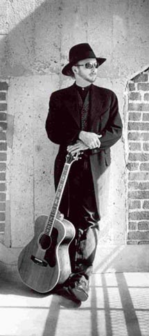 Roy Rogers by a window in a loft with his guitar